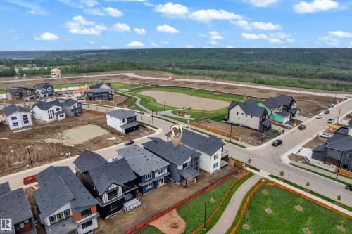 Aerial perspective of a developing residential community, featuring modern architectural homes with dark-toned roofs and varied exterior finishes - 7677 Kimiwan Crescent, Edmonton, AB 