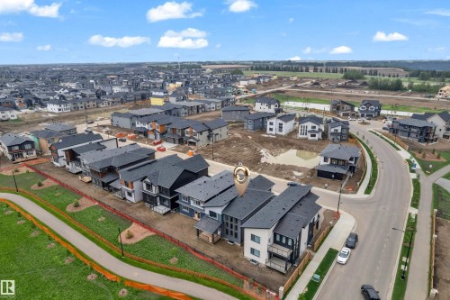 Modern townhome exterior featuring multiple balconies, a mix of light and dark siding, and a dark shingle roof - 7677 Kimiwan Crescent, Edmonton, AB 