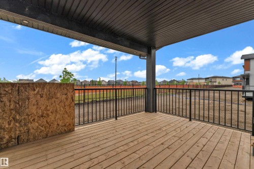 Expansive covered outdoor deck featuring wood plank flooring and black metal railings - 7677 Kimiwan Crescent, Edmonton, AB 