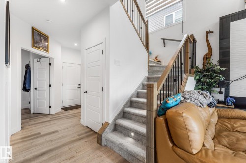 Staircase featuring wood handrails, black metal balusters, and integrated step lighting - 94 Elm Street, Fort Saskatchewan, AB 