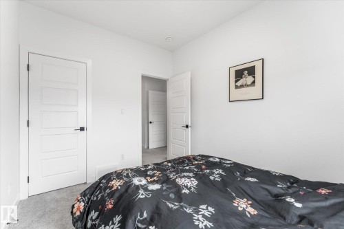 Light gray carpeted flooring paired with white walls, contemporary white paneled doors, and matte black hardware - 94 Elm Street, Fort Saskatchewan, AB 