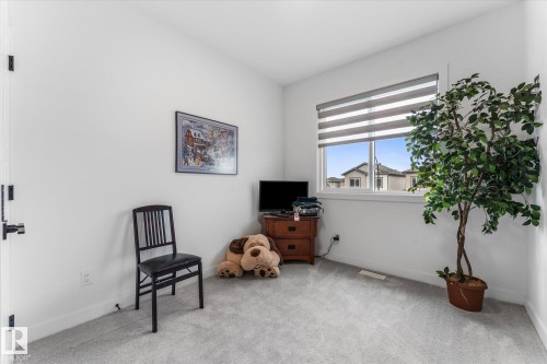 Carpeted room featuring a single window with horizontal blinds, white walls, and a white baseboard - 94 Elm Street, Fort Saskatchewan, AB 