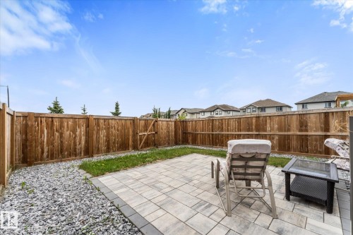 Expansive backyard featuring a paver patio with dark gray border, surrounding gravel landscaping, and a wooden privacy fence - 94 Elm Street, Fort Saskatchewan, AB 