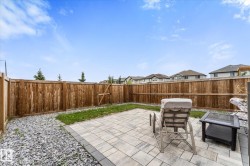 Expansive backyard featuring a paver patio with dark gray border, surrounding gravel landscaping, and a wooden privacy fence - 