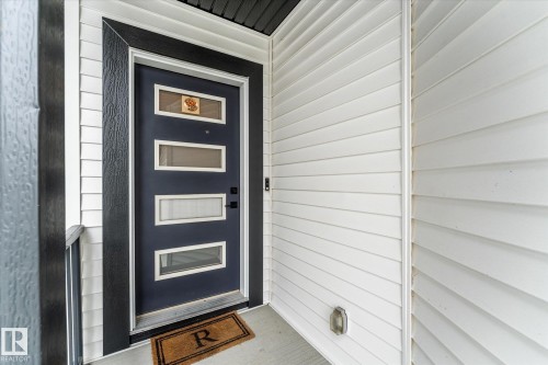 Contemporary front door with multiple rectangular glass inserts, matte black hardware, and an encompassing textured black trim - 94 Elm Street, Fort Saskatchewan, AB 