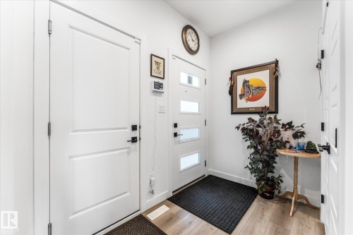 Entryway featuring a white paneled door, a white front door with frosted glass inserts, and wood-finish flooring - 94 Elm Street, Fort Saskatchewan, AB 