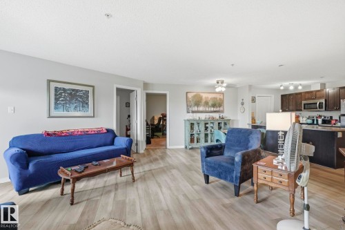 Open-concept living area featuring wood-finish flooring, light gray wall paint, and recessed ceiling lighting - 1223 9363 Simpson Dr, Edmonton, AB 