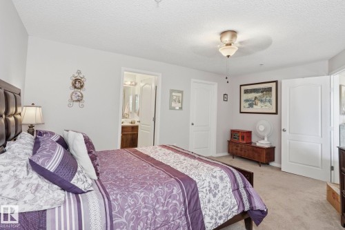 Spacious bedroom featuring light-colored carpet flooring, a ceiling fan with integrated lighting, and neutral-toned walls - 1223 9363 Simpson Dr, Edmonton, AB 