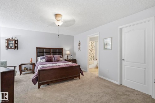 Spacious bedroom featuring neutral carpeting and light-toned walls - 1223 9363 Simpson Dr, Edmonton, AB 