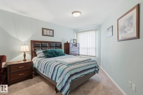 Carpeted bedroom featuring light blue walls and a window with vertical blinds - 1223 9363 Simpson Dr, Edmonton, AB 