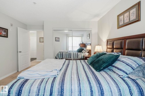 Bedroom featuring a paneled headboard, mirrored closet doors, and neutral wall paint - 1223 9363 Simpson Dr, Edmonton, AB 