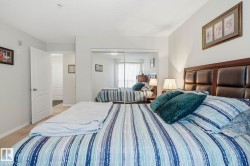 Bedroom featuring a paneled headboard, mirrored closet doors, and neutral wall paint - 