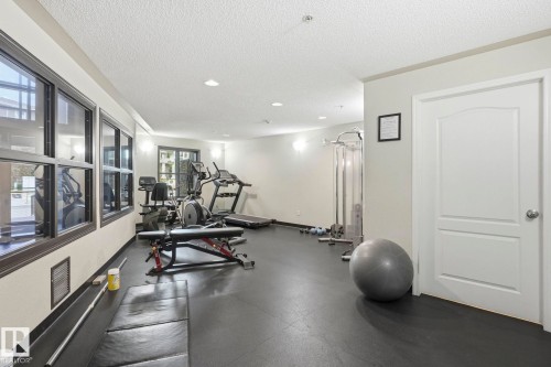 Dedicated fitness room featuring dark rubber flooring, recessed lighting, and wall-mounted sconces - 1223 9363 Simpson Dr, Edmonton, AB 