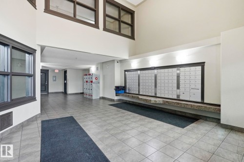 Spacious communal entry featuring tile flooring, a built-in mail center with a stone-finish shelf, and additional storage lockers - 1223 9363 Simpson Dr, Edmonton, AB 