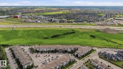 Aerial perspective showcasing multiple residential buildings with varying rooflines, extensive parking areas, and mature landscaping - 
