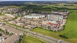 Aerial perspective showcasing a mixed-use development with residential buildings, commercial establishments, and ample surface parking - 