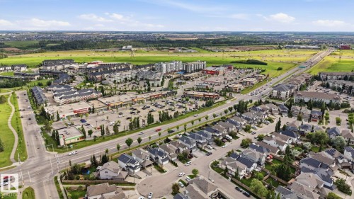 Aerial perspective showcasing a mixed-use development with residential properties, retail centers, commercial spaces, and ample parking - 1223 9363 Simpson Dr, Edmonton, AB 