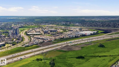 Aerial overview of a developed area featuring a prominent multi-lane highway, commercial retail centers, and residential housing - 1223 9363 Simpson Dr, Edmonton, AB 
