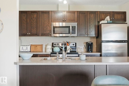 Kitchen featuring wood-finish cabinetry and a light-toned countertop - 1223 9363 Simpson Dr, Edmonton, AB 