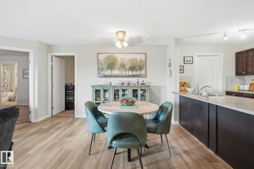 Open concept living area featuring wood-finish flooring, a ceiling-mounted light fixture, and a kitchen island with an undermount sink - 1223 9363 Simpson Dr, Edmonton, AB 