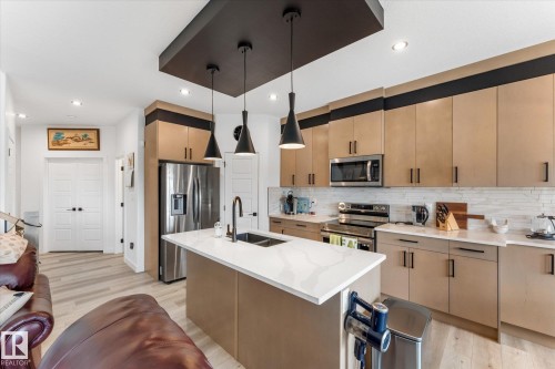 Modern kitchen featuring a central island with a white countertop and double basin sink - 92 Elm Street, Fort Saskatchewan, AB 