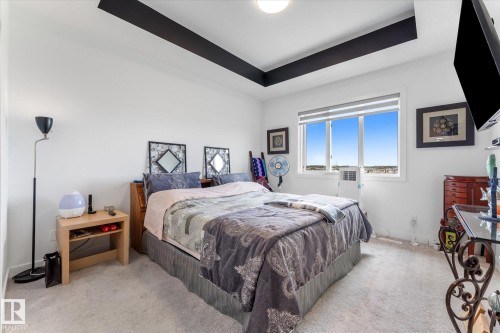 Bedroom featuring a tray ceiling with dark accent, white walls, and light-toned carpeting - 92 Elm Street, Fort Saskatchewan, AB 