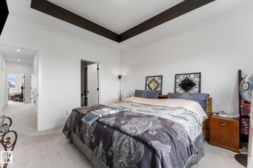 Bedroom featuring a tray ceiling with dark accent trim, white walls, and light-colored carpeting - 92 Elm Street, Fort Saskatchewan, AB 