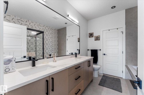 Modern bathroom featuring a dual vanity with light cabinetry, white countertops, and black hardware - 92 Elm Street, Fort Saskatchewan, AB 