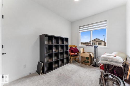 Bright room featuring a large window with horizontal blinds, neutral wall paint, and grey carpeting - 92 Elm Street, Fort Saskatchewan, AB 