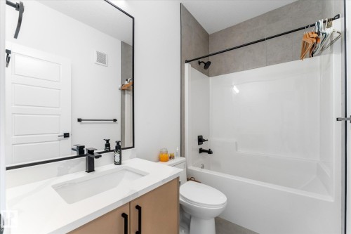 Modern bathroom featuring a rectangular vanity sink with a white countertop and wood-finish cabinetry - 92 Elm Street, Fort Saskatchewan, AB 