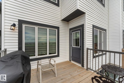 Exterior deck featuring natural wood planks, a dark gray metal railing, and white horizontal siding with dark gray trim - 92 Elm Street, Fort Saskatchewan, AB 