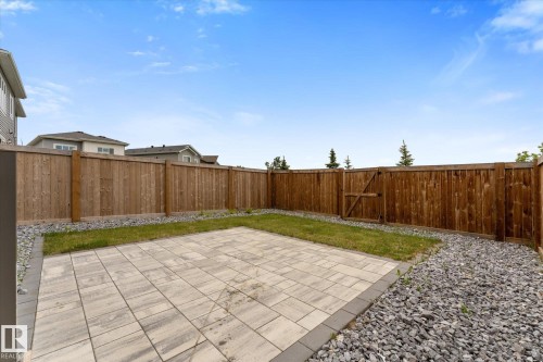 Private backyard featuring a paver patio area, a section of turf, and a perimeter fence with a gate - 92 Elm Street, Fort Saskatchewan, AB 