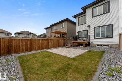 Private backyard featuring a wooden privacy fence, a concrete patio, a grass lawn, and gravel landscaping - 92 Elm Street, Fort Saskatchewan, AB 
