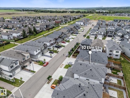 Aerial perspective showcasing a residential street with uniform detached homes and townhomes, grey shingle roofs, and concrete driveways - 92 Elm Street, Fort Saskatchewan, AB 