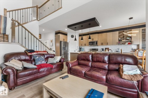 Bright open-concept living area featuring light wood-finish flooring and a two-story ceiling - 92 Elm Street, Fort Saskatchewan, AB 