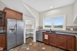 Kitchen featuring an expansive window, warm wood cabinetry, dark countertops, and a tiled backsplash - 