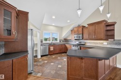 Kitchen featuring wood cabinetry, stainless steel appliances, a multi-tone tile floor, and a breakfast bar - 