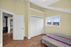 Room featuring wood-finish flooring, an angled ceiling, a white-framed window, and a bi-fold closet with panel doors - 