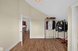 Room featuring wood-finish flooring, vaulted ceiling, and light-toned walls - 
