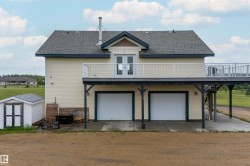 Two-car garage with white doors below an expansive second-story deck - 
