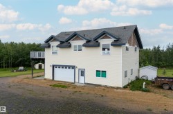 Multi-level residence featuring light-toned siding, a dark shingle roof, a two-car garage, and an upper-level balcony - 