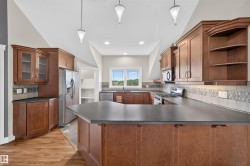 Kitchen featuring wood-finish cabinetry, stainless steel appliances, a center island with countertop seating, and a tile backsplash with decorative accents - 