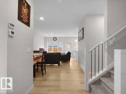 Open-concept living space featuring wood-finish flooring, recessed lighting, and a staircase with carpeted treads and metal balusters - 