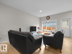 Living area with light wood-finish flooring, recessed lighting, and a large window featuring horizontal blinds - 