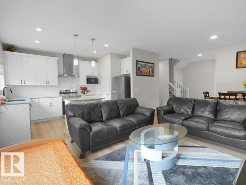 Contemporary kitchen with white shaker cabinetry, stainless steel appliances, subway tile backsplash, and a central island with countertop seating - 2039 13 Avenue, Edmonton, AB 