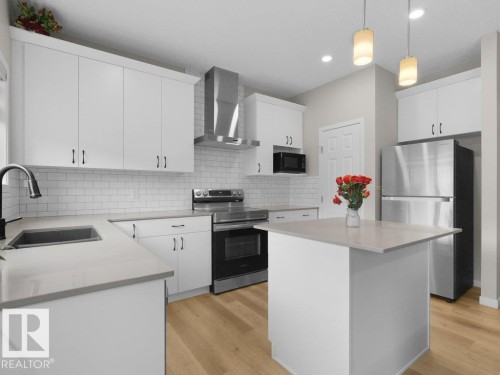 Modern kitchen featuring white cabinetry, light wood-finish flooring, a subway tile backsplash, and stainless steel appliances - 2039 13 Avenue, Edmonton, AB 
