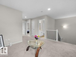 Carpeted landing area featuring recessed lighting, a white baluster staircase, and neutral wall tones - 
