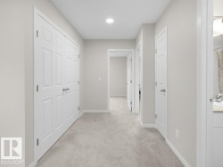 Neutral-toned hallway featuring light gray carpeting and white trim - 