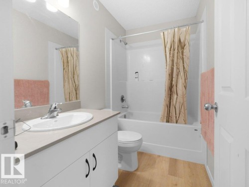 Bathroom featuring a white vanity with an integrated sink, chrome faucet, and light-toned countertop - 2039 13 Avenue, Edmonton, AB 