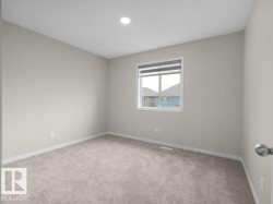 Neutral-toned room featuring a single window with blinds, recessed ceiling lighting, and light grey carpeting - 